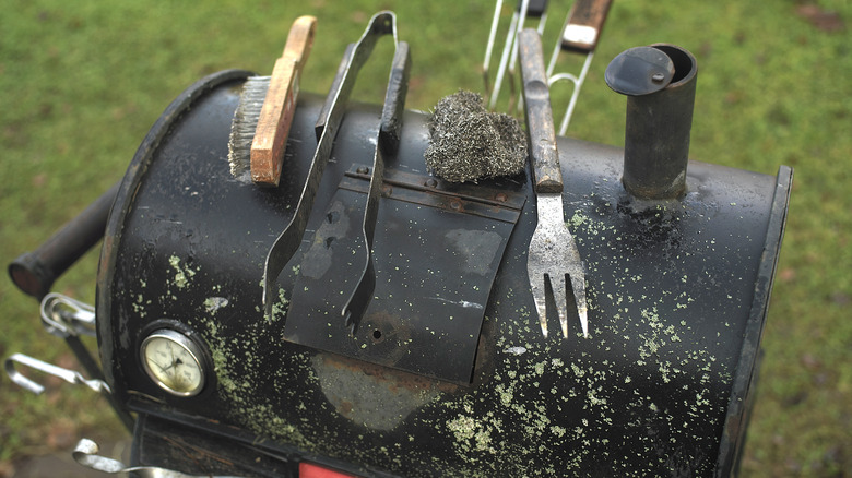 dirty grilling utensils on grill lid