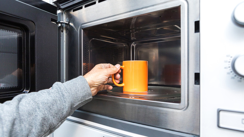 hand placing mug into microwave