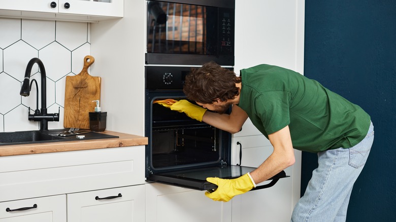 Man cleaning inside of oven 