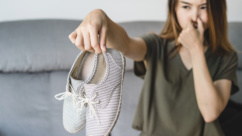 Woman holding smelly shoes