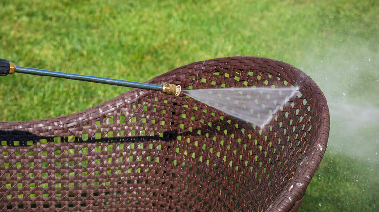 Person cleaning patio furniture with pressure washer