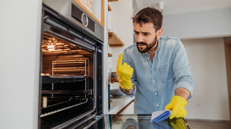 concerned man cleaning inside oven