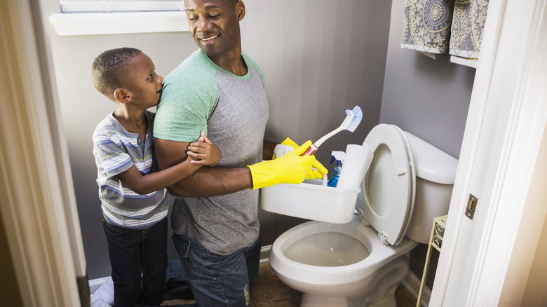 Father and son cleaning a toilet