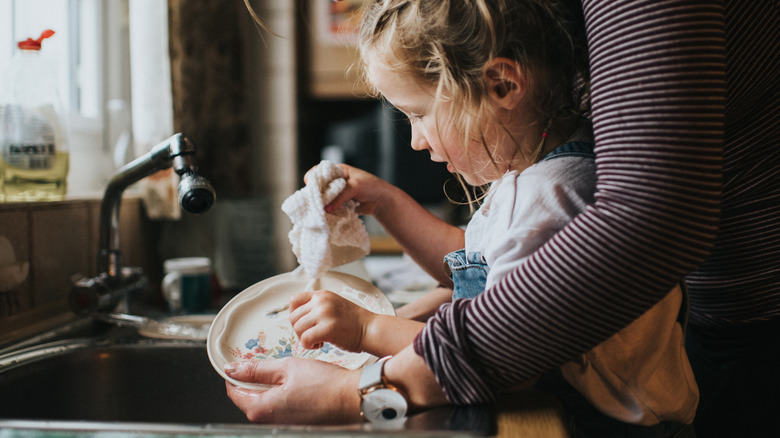 A child helping an adult do the dishes