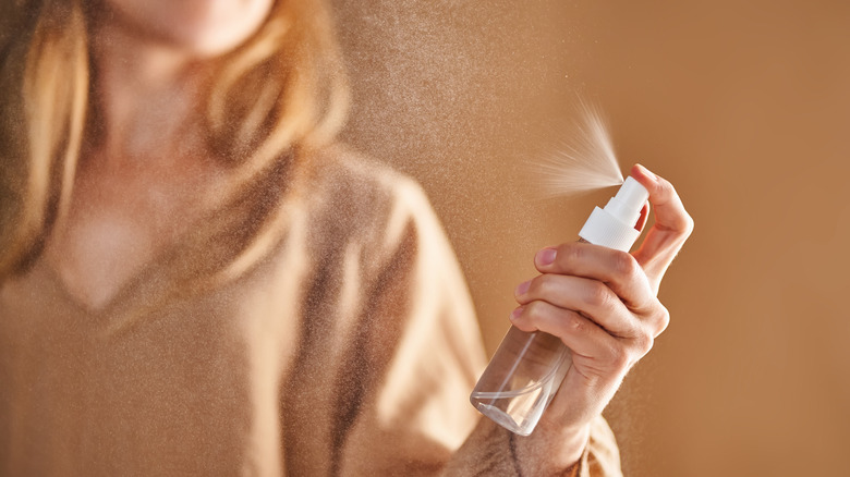 A person spritzing liquid from a spray bottle