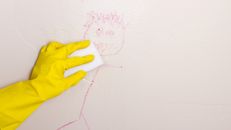 Hand cleaning marks off of a wall with a Magic Eraser