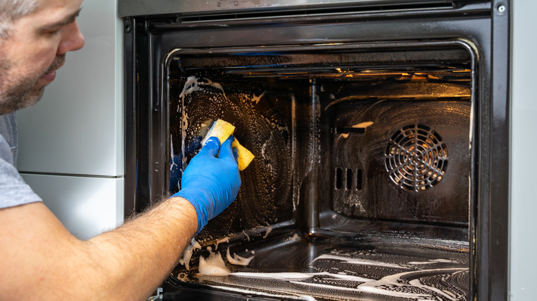 person scrubbing oven