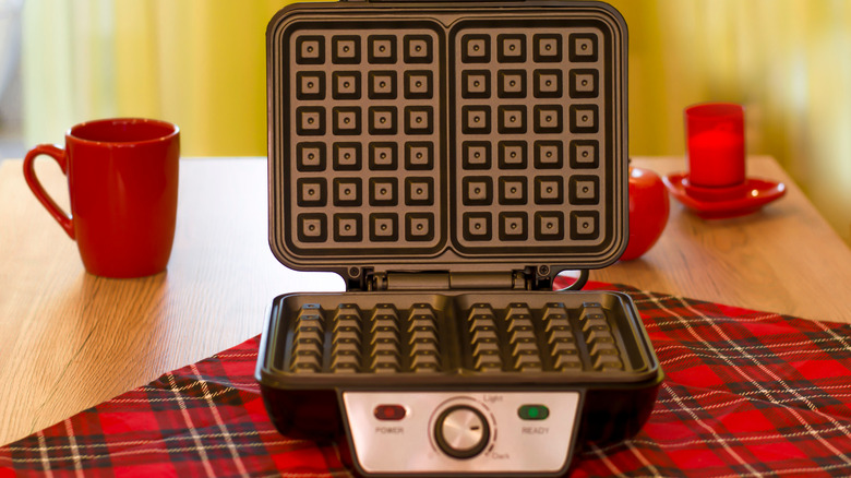 Waffle iron on red checkered blanket 