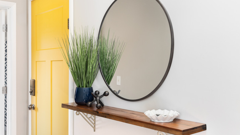 floating shelf in entryway with mirror hanging above