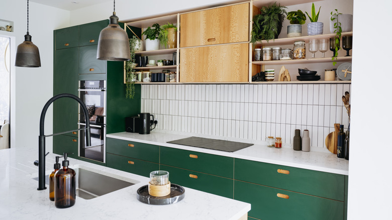 Kitchen with pendant lights, green colored cabinets, and tile backsplash