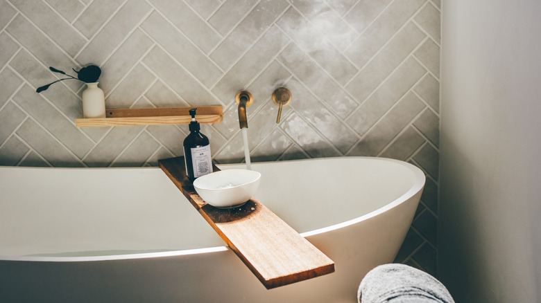 modern bathtub with wooden tray set across it