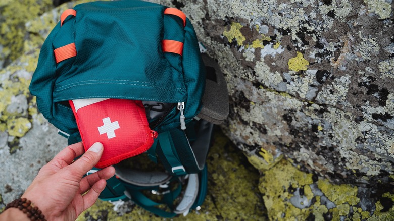 person putting first aid kit in bookbag