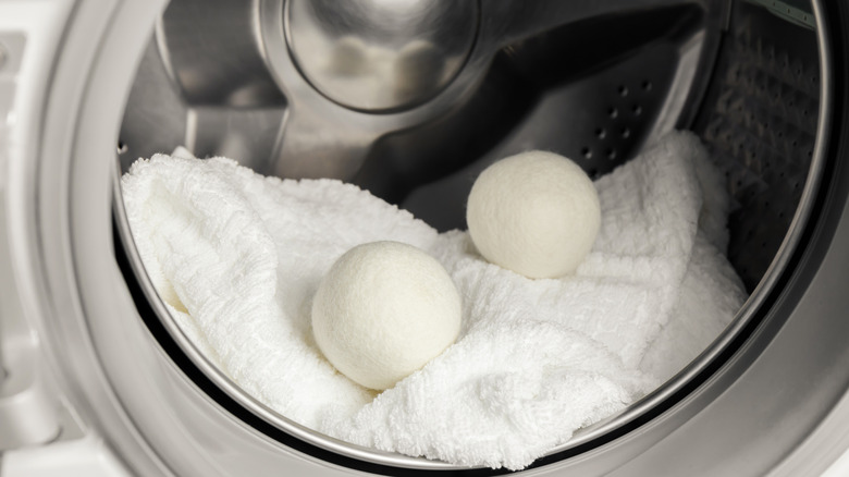 Wool dryer balls sitting a dryer with a towel