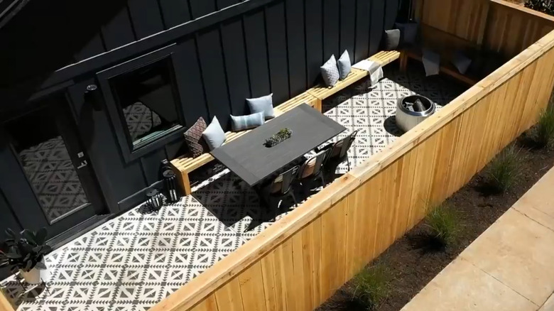 Secluded outdoor dining area with privacy fence and patterned concrete floor in "Fixer to Fabulous" Season 2, Episode 6