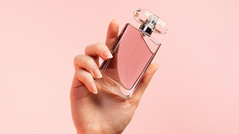 Bottle of pink perfume in hand