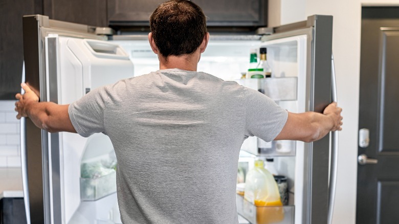 Man in gray shirt opening refrigerator