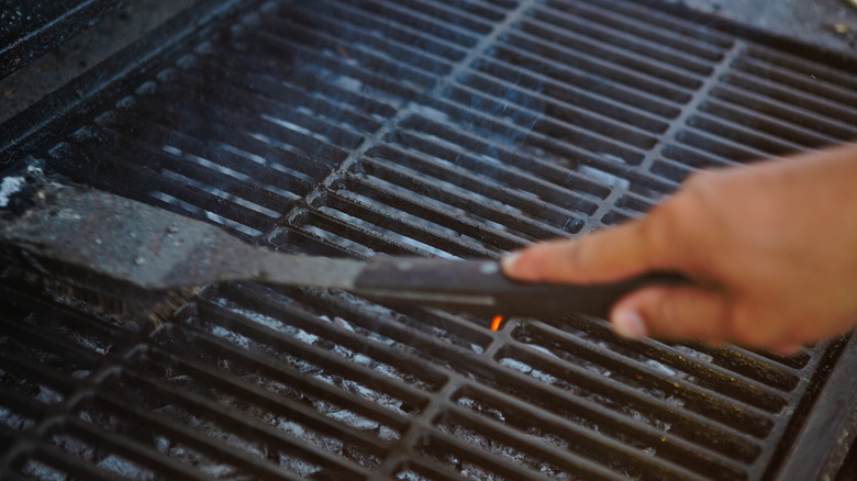 person scraping dirty outdoor grill