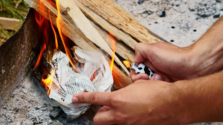 person starting fire with newspaper