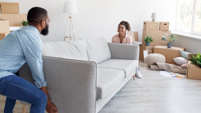 couple moving gray couch