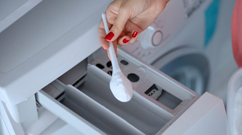 hand putting soap in washer