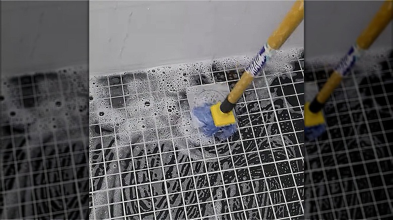 person clean shower flowers with broom