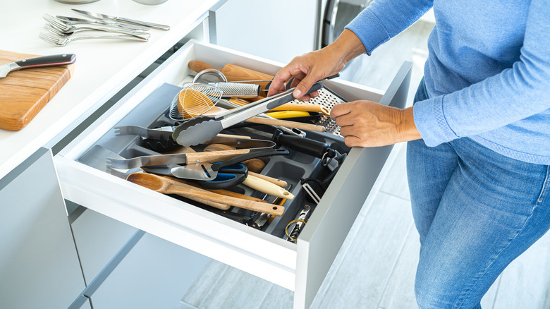 woman organizing kitchen utensils in drawer