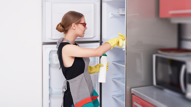 Woman wiping out refrigerator interior
