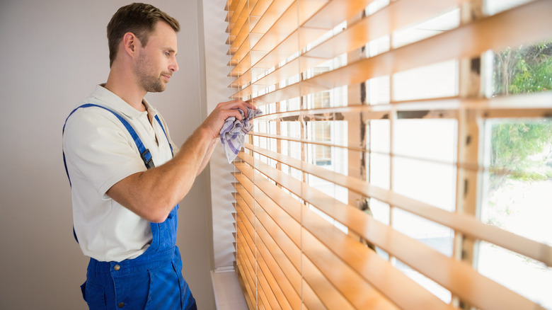 Man wiping down blinds