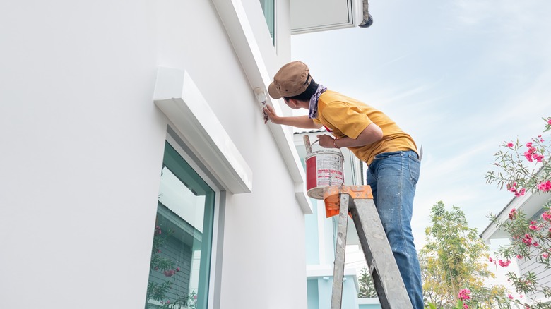 Man on ladder painting home