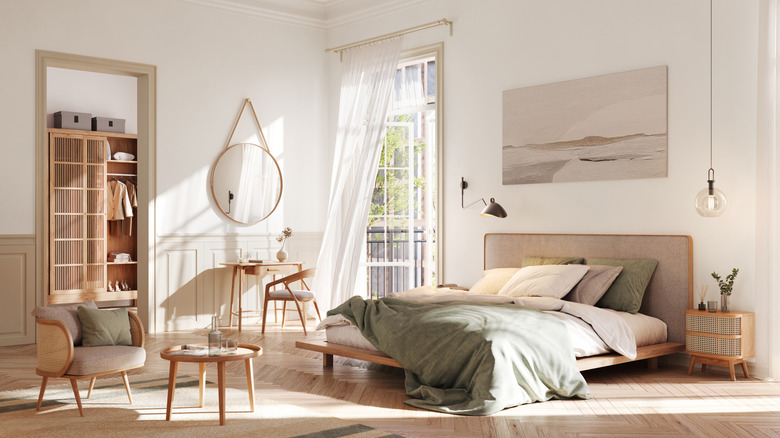 A neutral bedroom with breezy curtains and a Scandinavian style chair