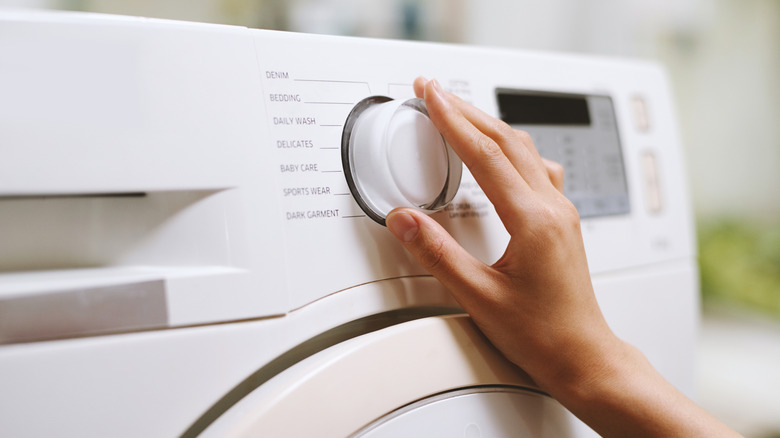 Hand adjusting laundry cycle on washing machine