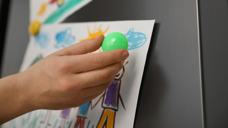 Hand placing magnet on fridge