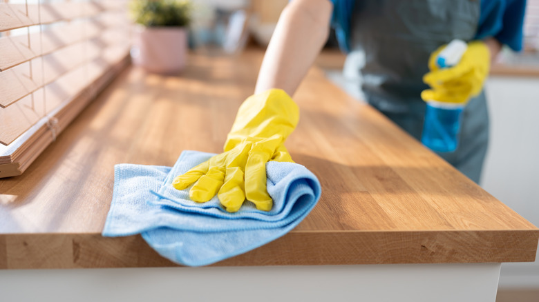 Person cleaning countertop with blue microfiber cloth