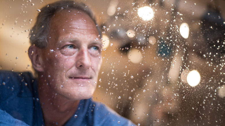 Man watching rain at window