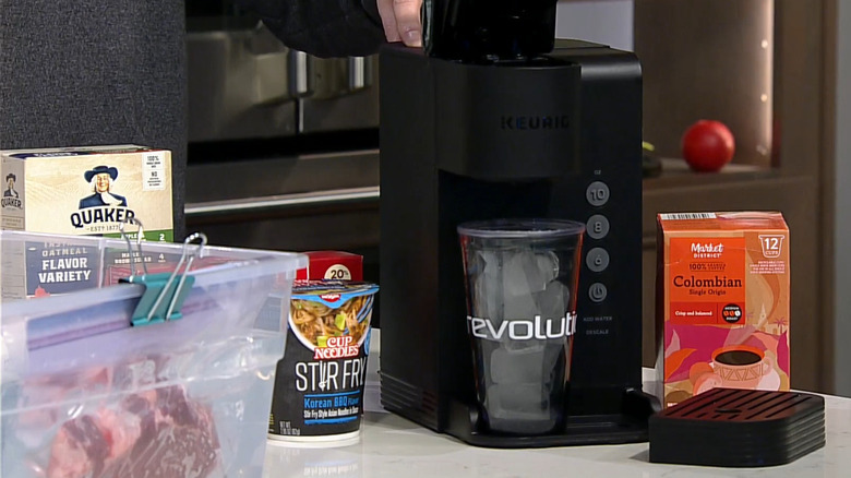 Close up of Keurig with large cup of ice under it and other food nearby