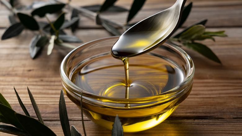 A spoon dipping into a bowl of olive oil