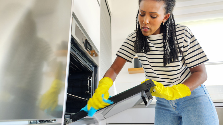 Person cleaning an oven using a microfiber towel