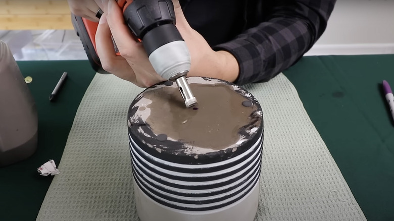 man drilling drainage hole in pot