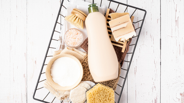 A wire basket is full of natural cleaning supplies like dish soap and baking soda