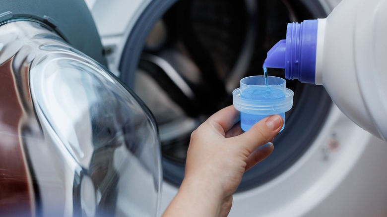 person pouring laundry detergent