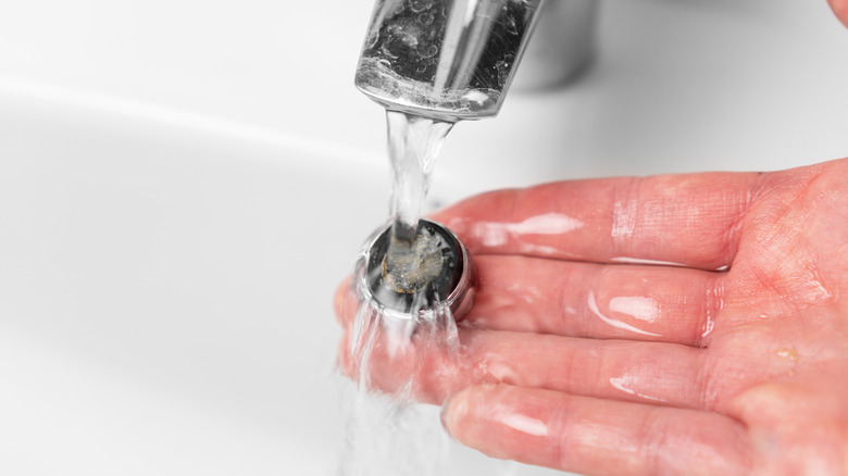 Person holding aerator under sink