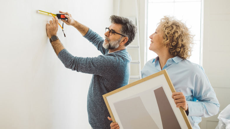 Couple measuring wall to hang picture frame