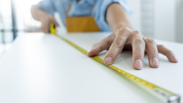 Man measuring a piece with tape measure