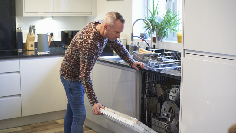 A man opens a dishwasher.