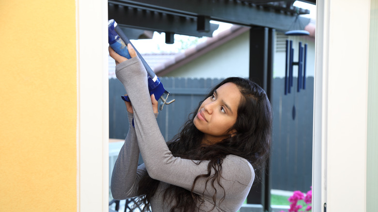 Woman caulking a door