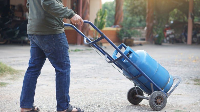 A person pushing a propane tank