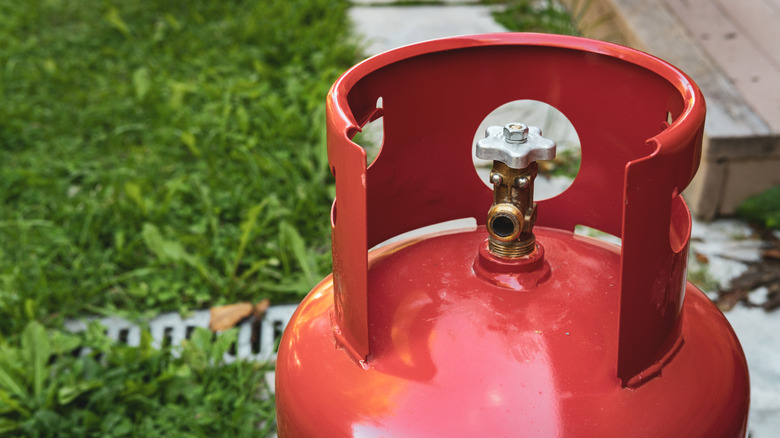 A propane tank in front of a grill