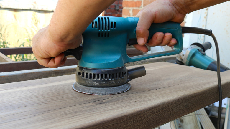 The person is using a handheld sander.