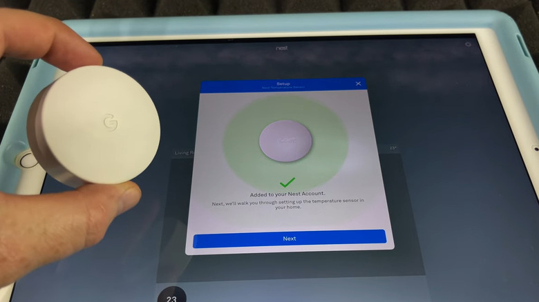 Hand holding a Nest sensor above an Ipad to connect it to the system