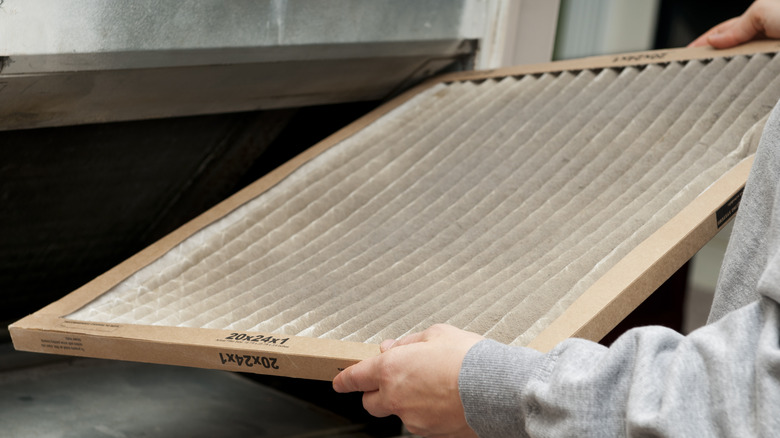 Hand removing a dirty air filter from an HVAC